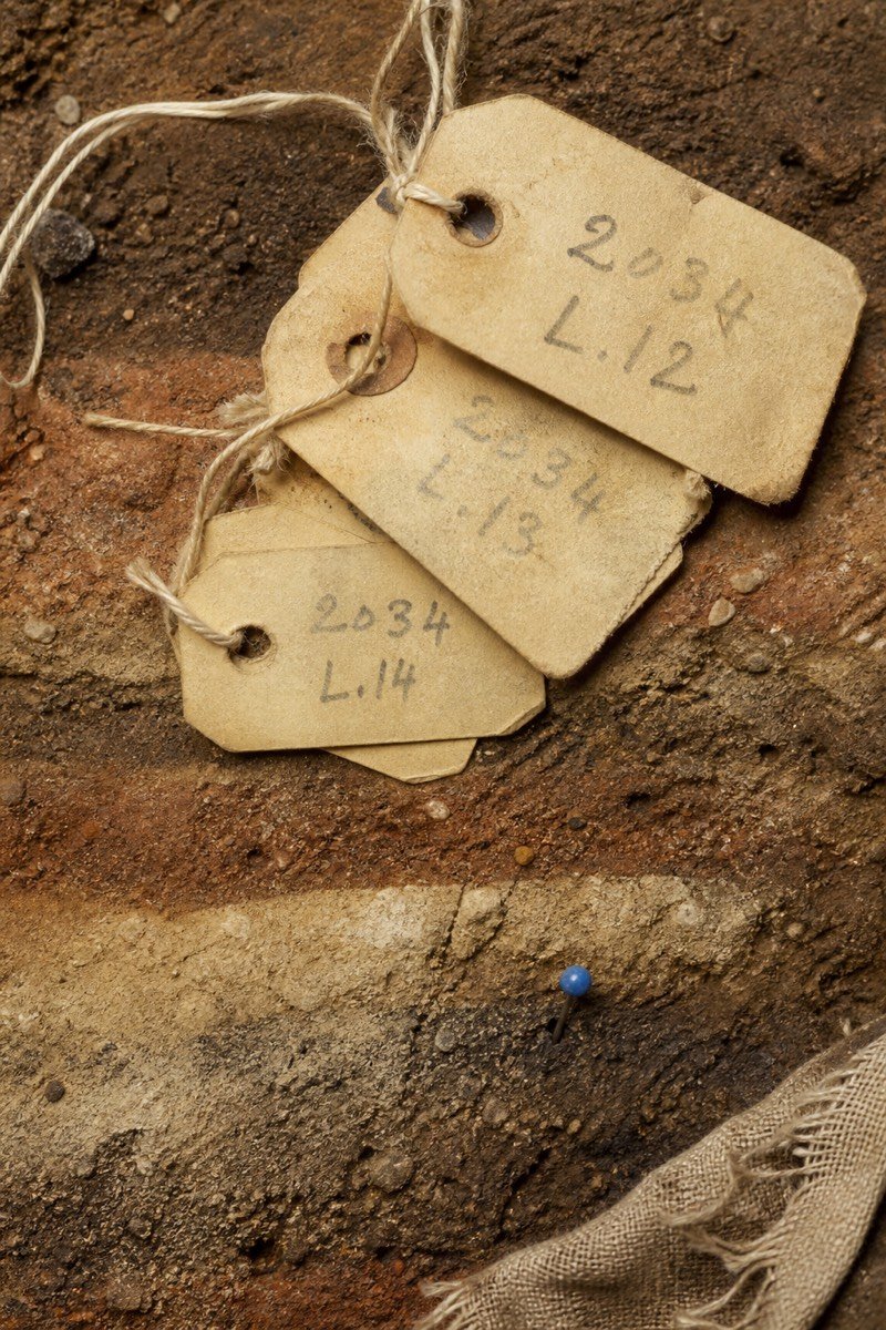 Aged yellow context tags with graphite numbers on soil